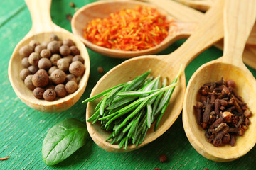 Wooden spoons with fresh herbs and spices on wooden background