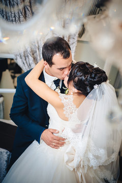 Charming bride with groom embraces and kisses on their wedding