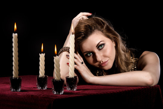Beautiful young woman with bright green eyes near the candles