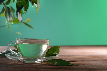 Cup of green tea on table on green background