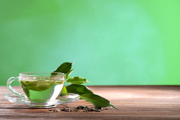 Cup of green tea on table on green background