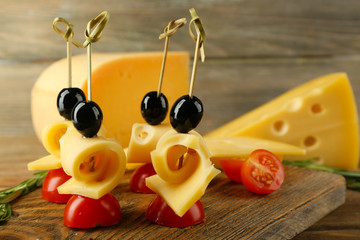 Cheese canapes with cherry tomatoes and olives on wooden background
