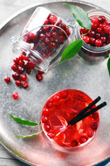 Compote with red currant in glassware on metal tray on wooden table, top view