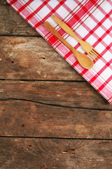 Obraz premium Checkered napkin with fork and spoon on wooden table background
