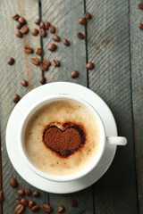 Cup of cappuccino with heart of cocoa on wooden table