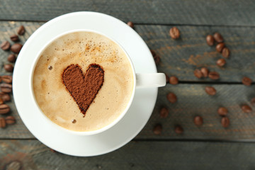 Cup of cappuccino with heart of cocoa on wooden table