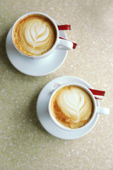 Cups of cappuccino with heart on foam on table in cafe