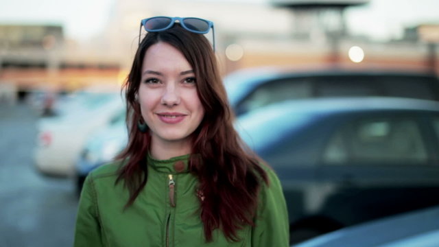 Young woman holding keys to new car and smiling at camera