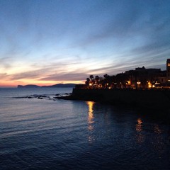 Fototapeta premium sunset and city lights at alghero, sardinia, italy