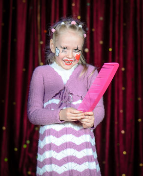 Girl Wearing Clown Make Up Holding Over Sized Comb