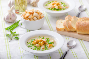 Garlic soup with croutons, spring onions and chives