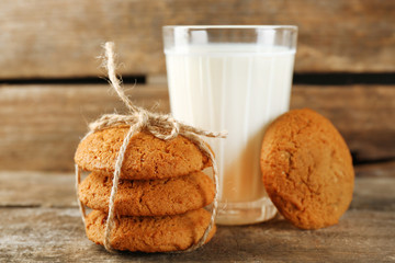 Tasty cookies and glass of milk on rustic wooden background