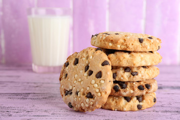 Tasty cookies and glass of milk on color wooden background