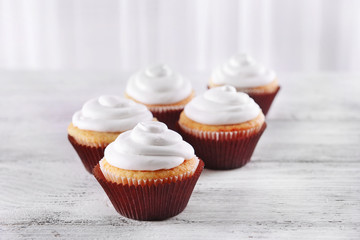 Delicious cupcakes on table on light background