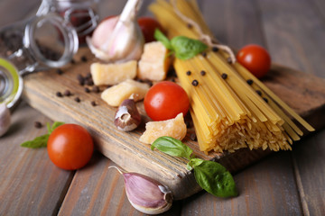 Raw pasta with cheese and vegetables on wooden background