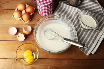 Preparation cream with eggs in glass bowl on wooden background