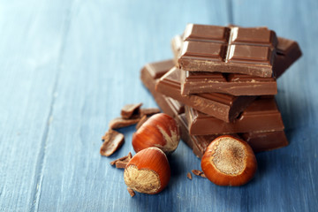 Pieces of chocolate with hazelnut on wooden table, closeup