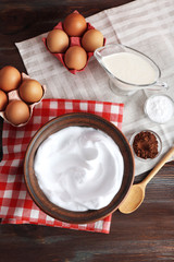 Whipped egg whites and other ingredients for cream on wooden table, top view