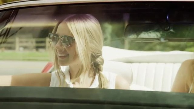 Close up tracking shot of women waving from convertible car / Pleasant Grove, Utah, United States