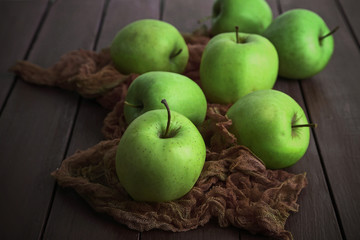 Green apples on wooden table with fabric, closeup