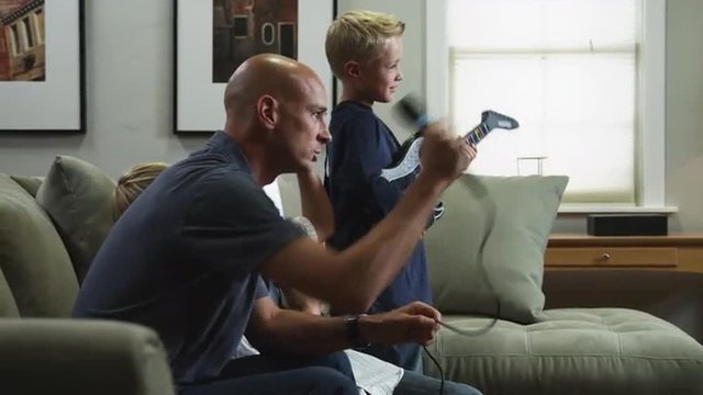 MS DS Father with two sons (8-9, 10-11) singing and playing electric guitars / Orem, Utah, USA