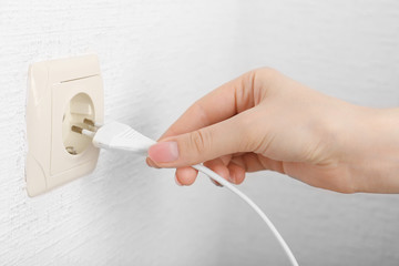 Hand putting plug in electricity socket close up