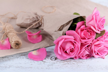 Beautiful pink roses on wooden table with parchment, closeup
