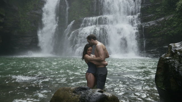 Wide panning slow motion view of couple kissing in swimming hole near waterfall / Santa Juana, , Costa Rica
