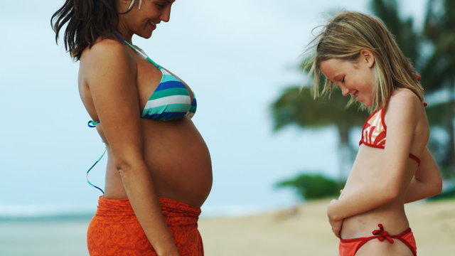 girl putting ear to pregnant woman's stomach
