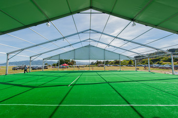 Huge white tent with green floor in field