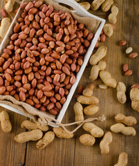 Peanuts in white box on  wooden table.