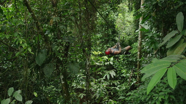 High angle wide shot of man ziplining in rain forest / Quepos, Puntarenas, Costa Rica