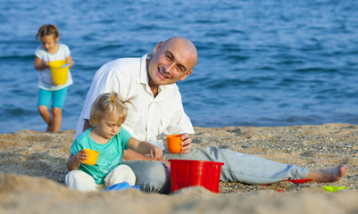 Fototapeta na wymiar Dad and daughters on beach.