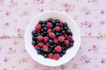 Mix of wild raspberry and black currant over flower background