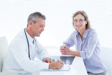 Patient smiling at camera while doctor taking notes