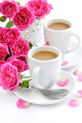 Cups of coffee and pink roses on white background