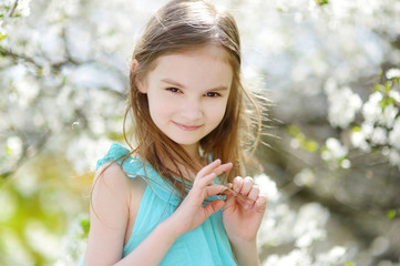 Adorable little girl in blooming cherry garden