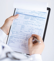 male doctor holding prescription paper in hand