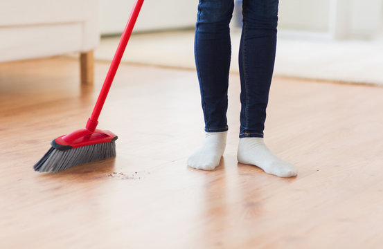 close up of woman legs with broom sweeping floor