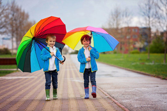 Two adorable little boys, walking in a park on a rainy day, play
