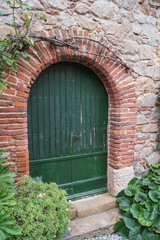 Fototapeta na wymiar arched green wooden door in a wall of stone
