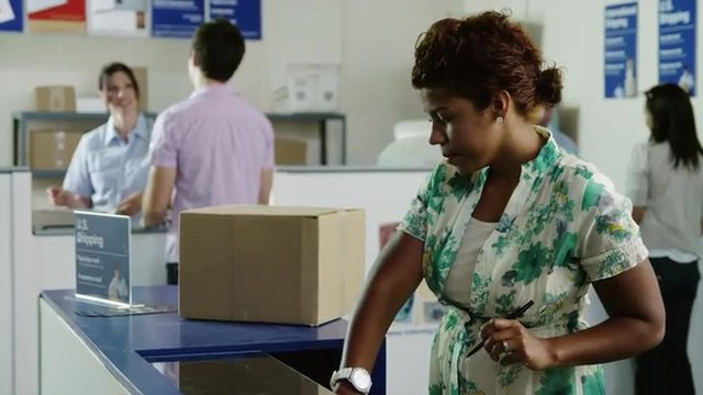 MS TU Woman carrying cardboard box arriving in post office / Orem, Utah, USA