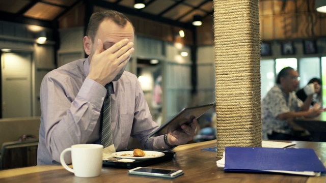 Unhappy businessman with smartphone and tablet 