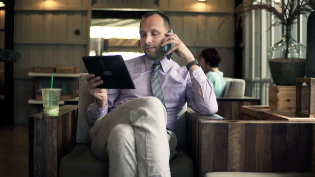 Young businessman with tablet computer talking on cellphone 
