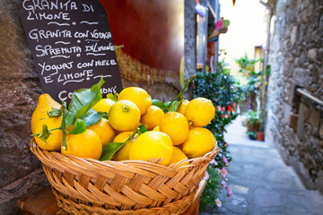 Wicker basket full of lemons on the italian street od Corniglia - obrazy, fototapety, plakaty