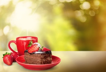 Closeup. Delicious chocolate cake with cream and berries and cup