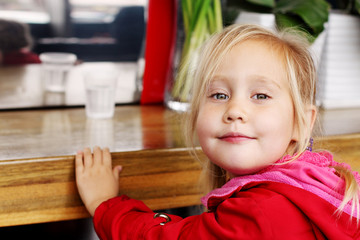 Adorable 4 years old girl sitting in cafe