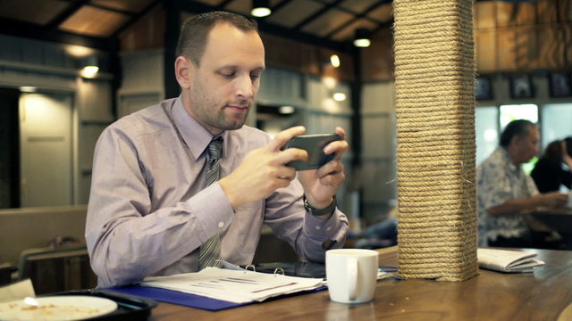 Young businessman playing game on smartphone in cafe
