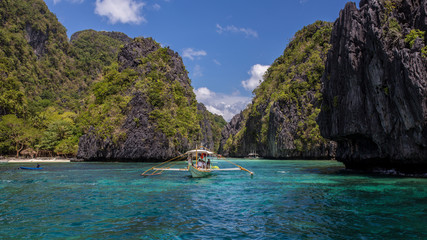 Fototapeta na wymiar Palawan island blue turquoise Lagoon with a boat and green mountains in Philippines