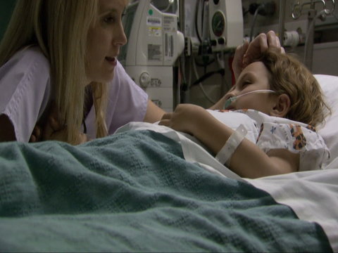 Nurse talking to and comforting child in hospital bed
